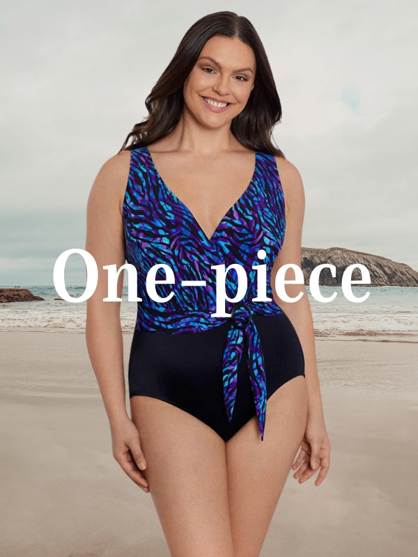 lady wearing a one piece with a black background and colorful tropical print 