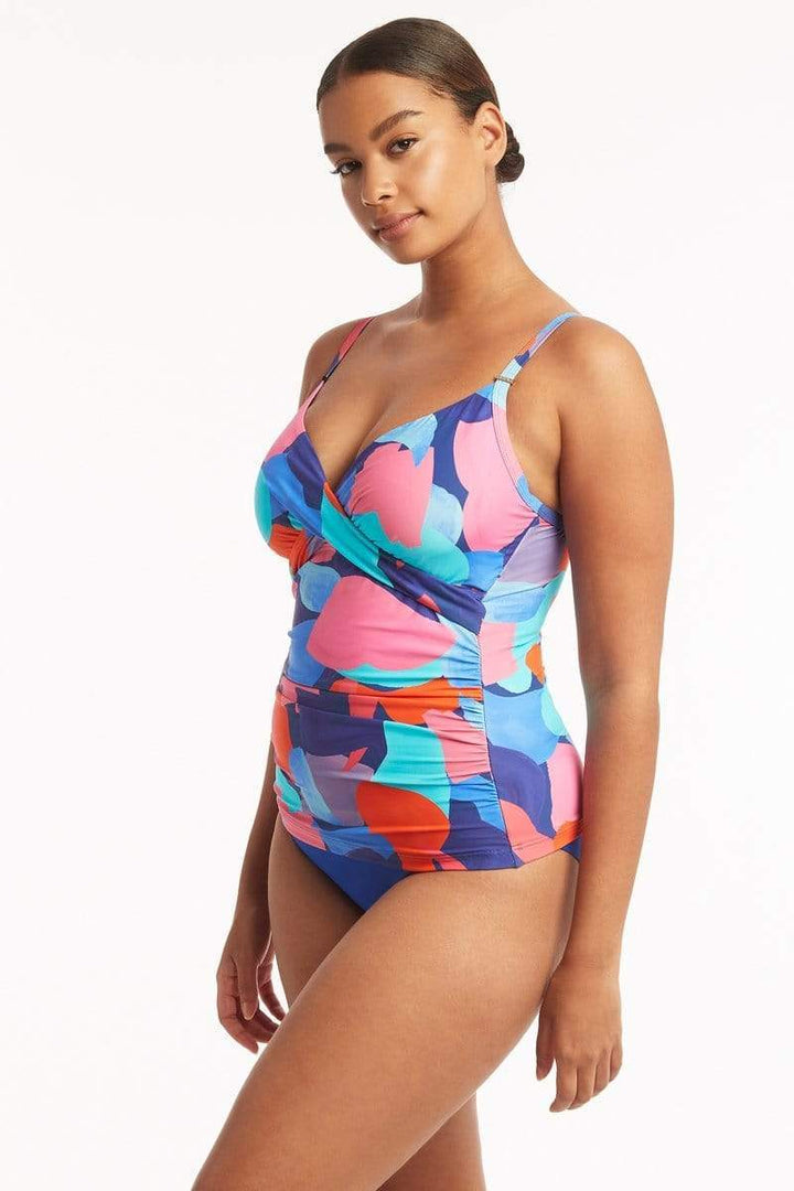 Style # SL3206PB   Sea Level Royal Print Paintball Twist Front Tankini  Escape to a tropical paradise with Sea Level's new paintball print, a hand painted and unexpected take on camouflage in exciting shades of blue, pink and corals. The flattering twist front design hides a comfortable and supportive shelf bra. The mid rise bottom will hug your curves in a beautiful cobalt blue. 